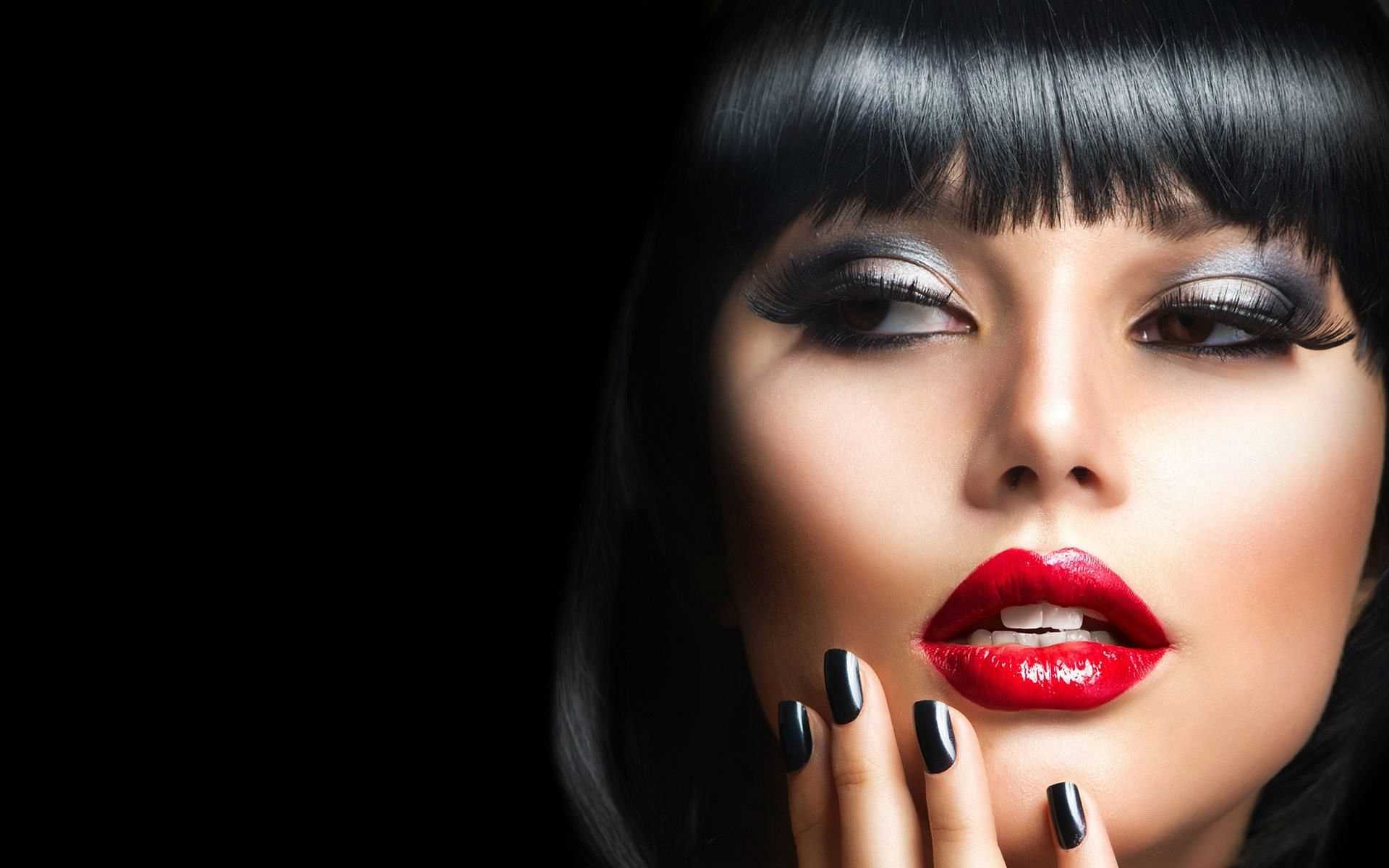 Close-up of a woman with bold makeup and polished nails.